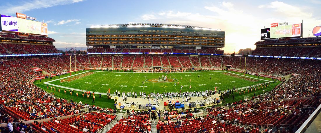 A packed American football stadium at sunset