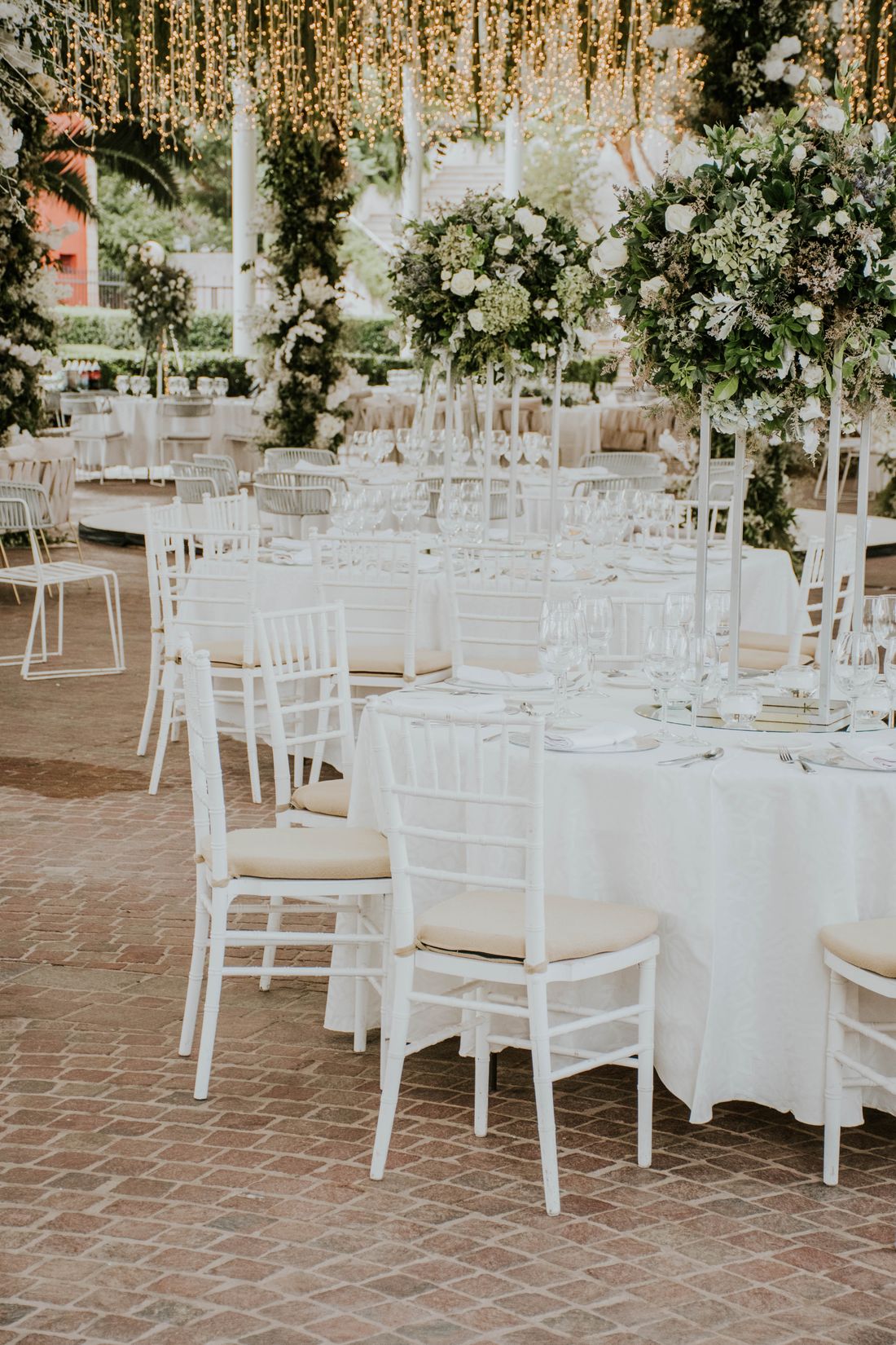 An outdoor wedding reception set with white chairs and flowers